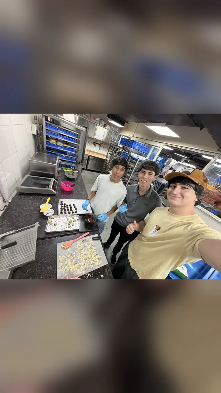 Three of us in the kitchen, next to trays of raspberries being dipped in chocolate.
